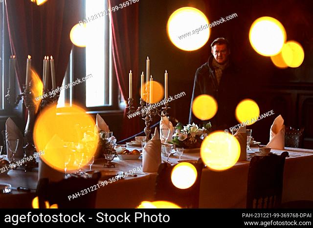 20 December 2023, Saxony-Anhalt, Wernigerode: View through festive lighting of the Christmas table decorations in the banqueting hall of Wernigerode Castle