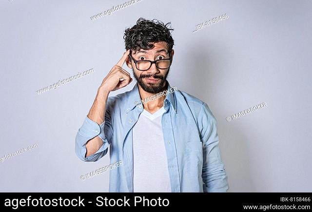 Young man wondering with his finger on isolated background, A guy thinking with his finger on his head