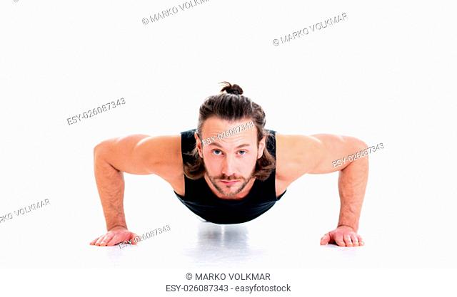 young man doing press-up in front of white background