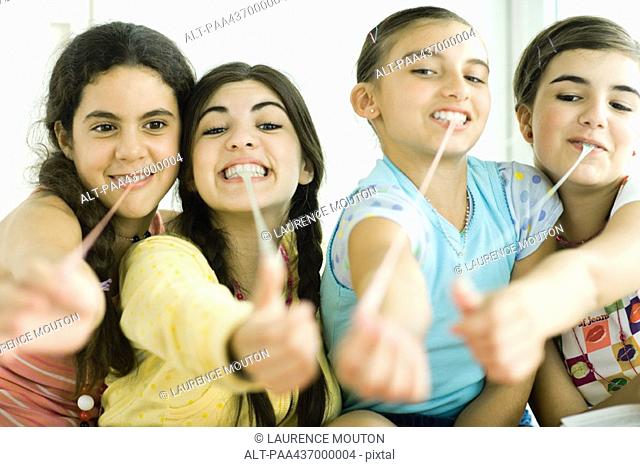Four young female friends pulling chewing gum out of mouths