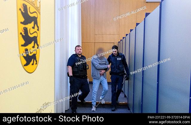 21 December 2023, Baden-Württemberg, Ulm: Judicial officers lead a man handcuffed and shackled into the courtroom at the regional court