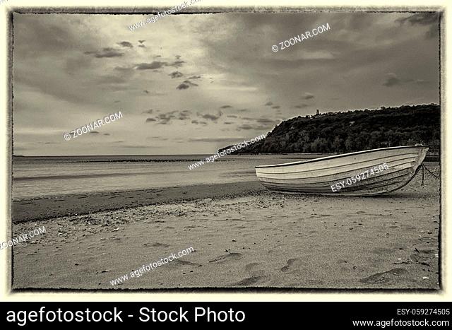Black and white seascape of a wooden boat on the beach. Vintage view