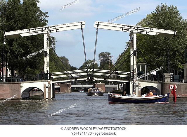 Swing bridge with tour boat and open traditional power boat Amsterdam The Netherlands