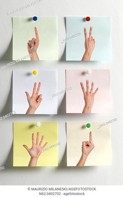 Five colorful Post It messages fixed to the wall with images of fingers indicating numbers and one with the middle finger