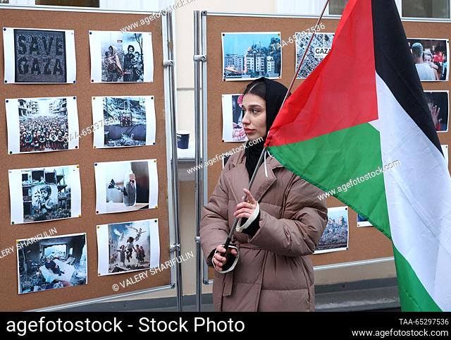 RUSSIA, MOSCOW - NOVEMBER 28, 2023: A woman holding a Palestinian flag looks at photographs showing devastation in the Gaza Strip