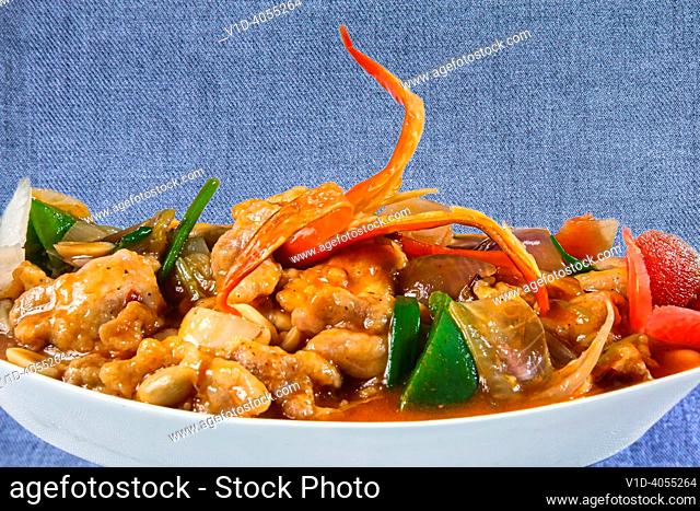Boneless chilli chicken with red peppers is a exotic and mouthwatering Thai food served in a ceramic bowl on a white background