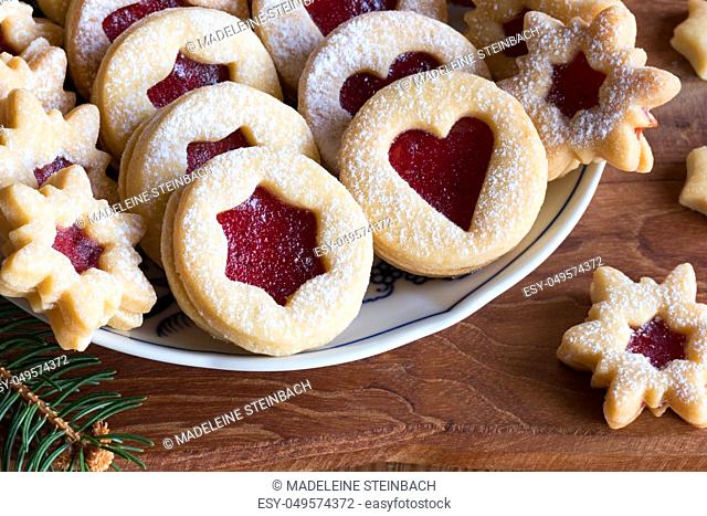 Linzer Christmas cookies filled with strawberry jam and dusted with sugar, arranged on a plate