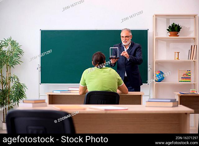 Aged physics teacher and young student in the classroom