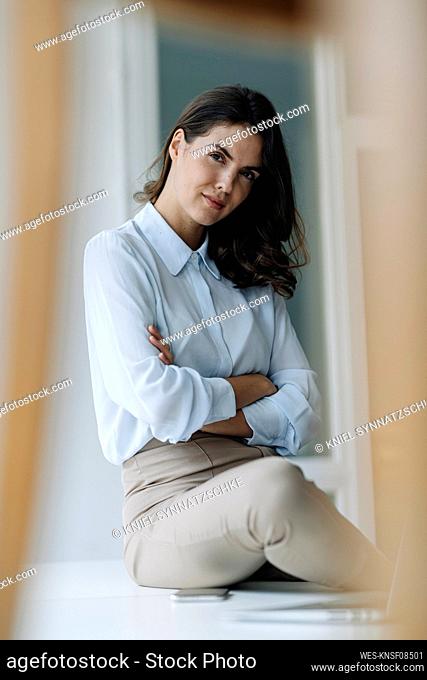 Businesswoman with arms crossed sitting on floor at office