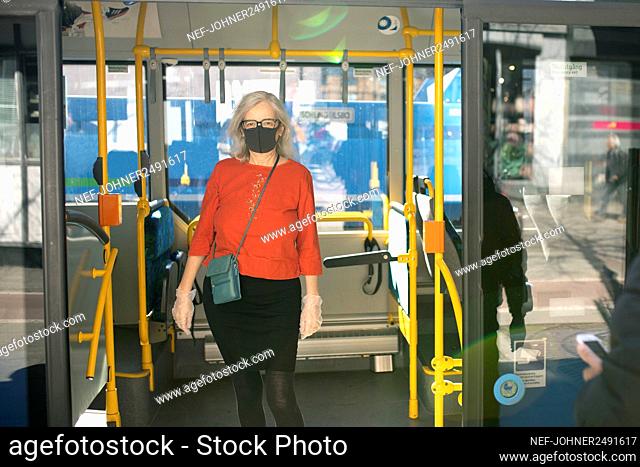 Woman wearing face mask standing in bus