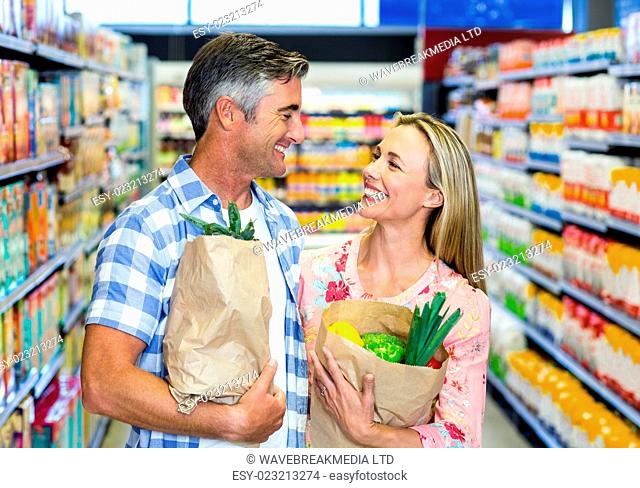 Smiling couple with grocery bags at the supermarket
