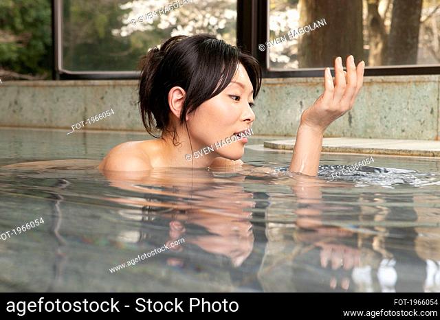 Young woman soaking in water at Onsen spa
