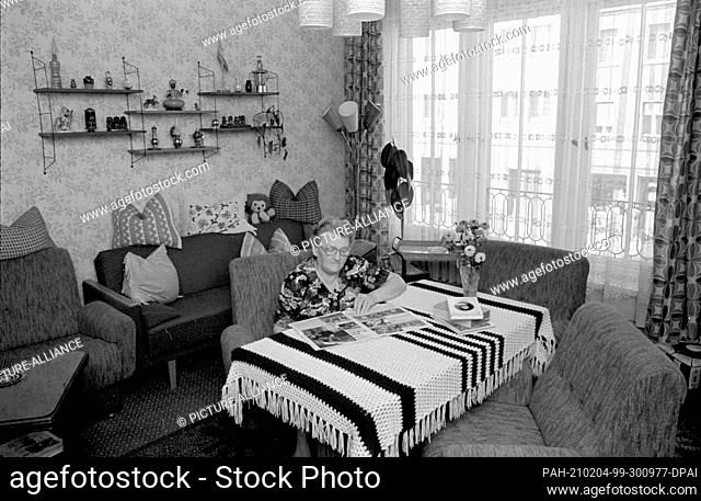 15 October 1984, Saxony, Eilenburg: The GDR district town of Eilenburg in autumn 1984 - an elderly woman sits in her living room reading a magazine