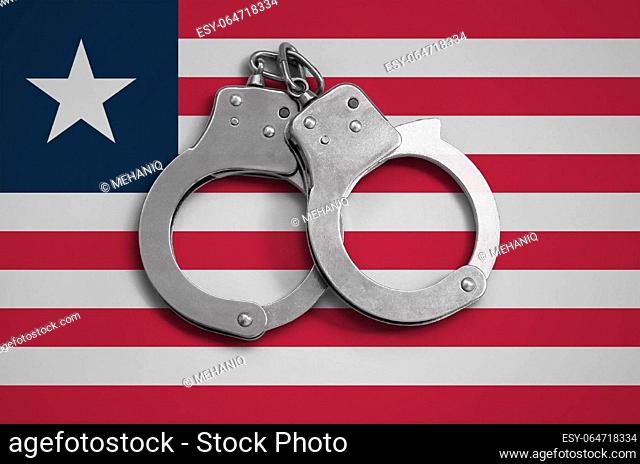 Liberia flag and police handcuffs. The concept of observance of the law in the country and protection from crime