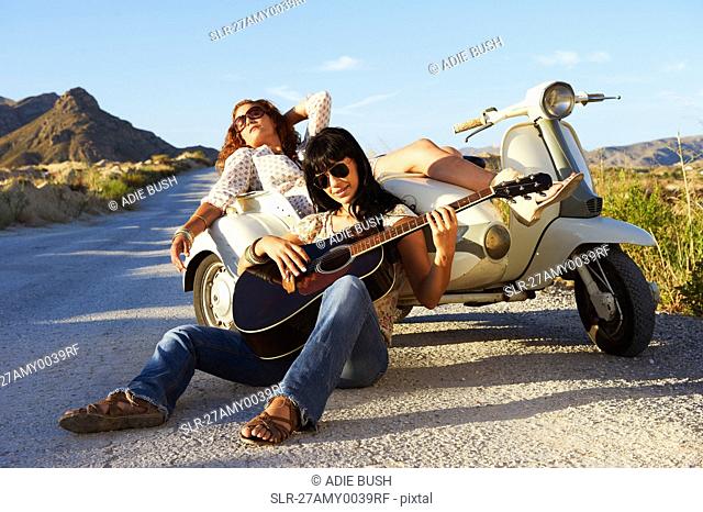 Women resting by road with motorbike