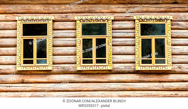 Windows of old log house with carved wooden trim