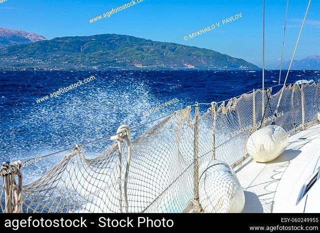 Greece. A sunny and windy day in the Gulf of Corinth. Left side of a white sailing yacht and water spray