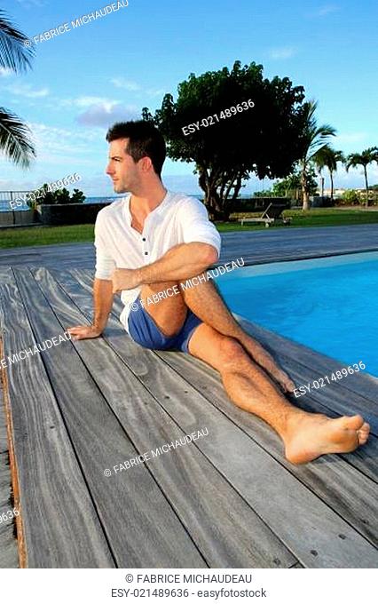 Young man doing stretching exercises on pool deck