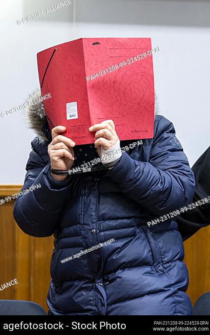 08 December 2023, Lower Saxony, Bückeburg: The defendant stands in a courtroom in Bückeburg district court before the start of the trial and holds a folder of...