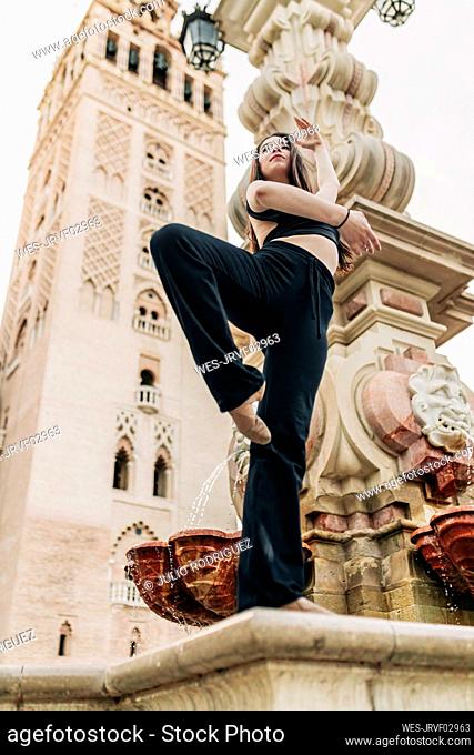 Ballet dancer standing on one leg on fountain in Spain