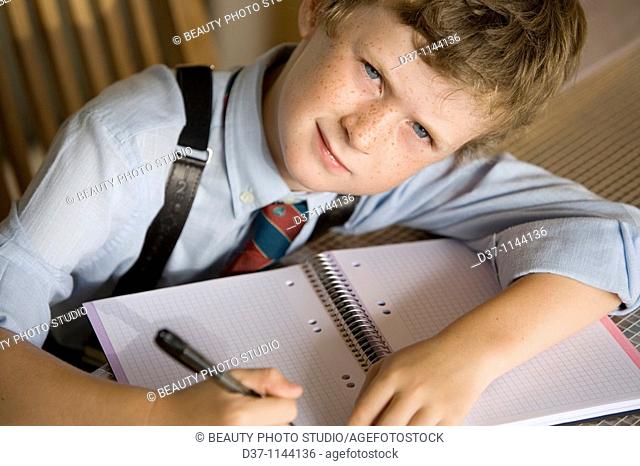 Caucasian boy writing on a notebook
