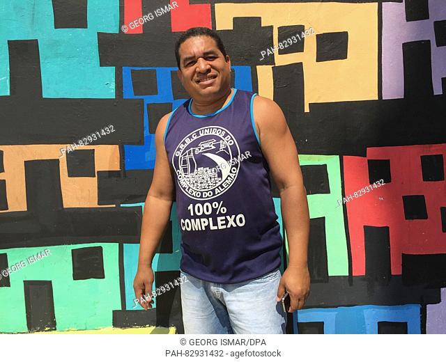 Cleber Araujo pictured in front of a colourfully-painted wall, with which he and his wife want to take a stand against violence and illustrate the colourful...