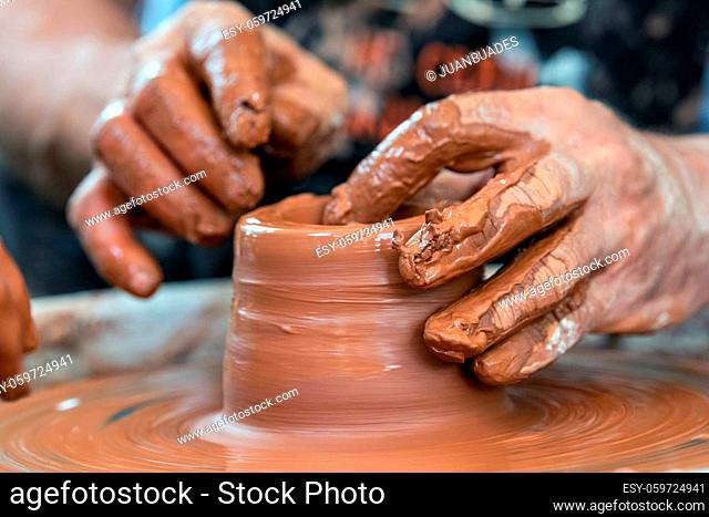 Hands of the potter. The potter makes pottery dishes on potter's wheel. The sculptor in workshop makes clay product closeup