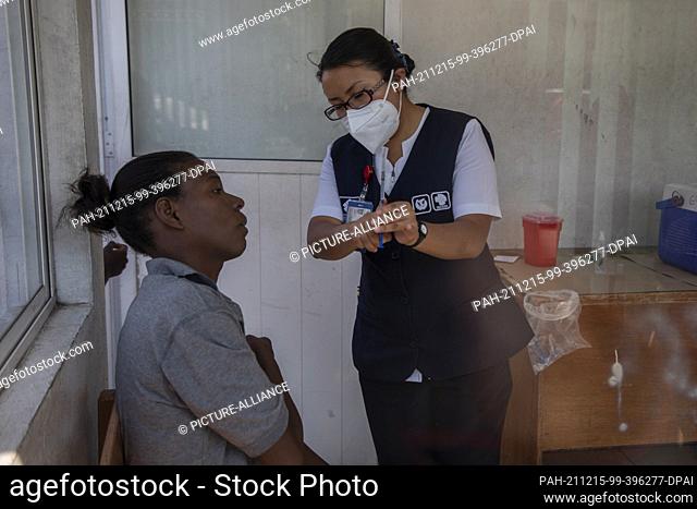 14 December 2021, Mexico, Mexiko-Stadt: A health worker shows a migrant the vaccine she is being given against influenza