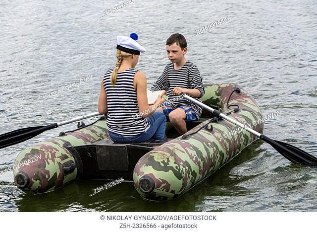 Boy and girl of twelve years in a rubber boat on the river going
