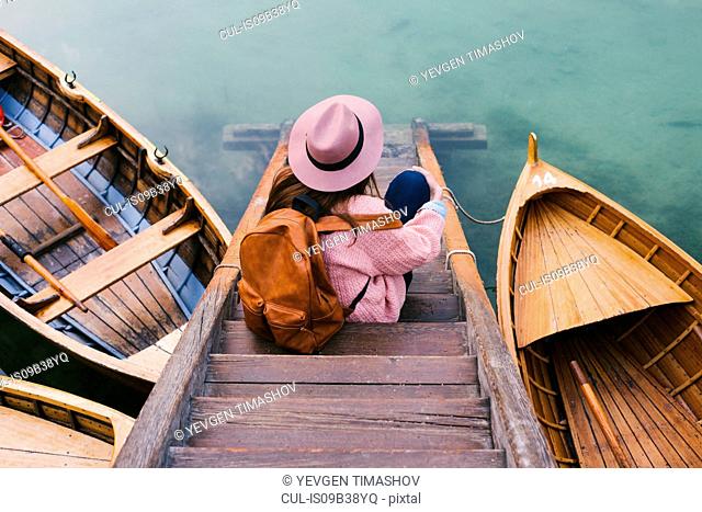 Woman relaxing on pier, Lago di Braies, Dolomite Alps, Val di Braies, South Tyrol, Italy