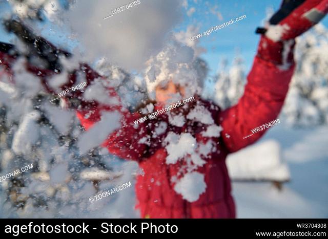 little girl having fun throwing fresh snow at beautiful sunny winter day