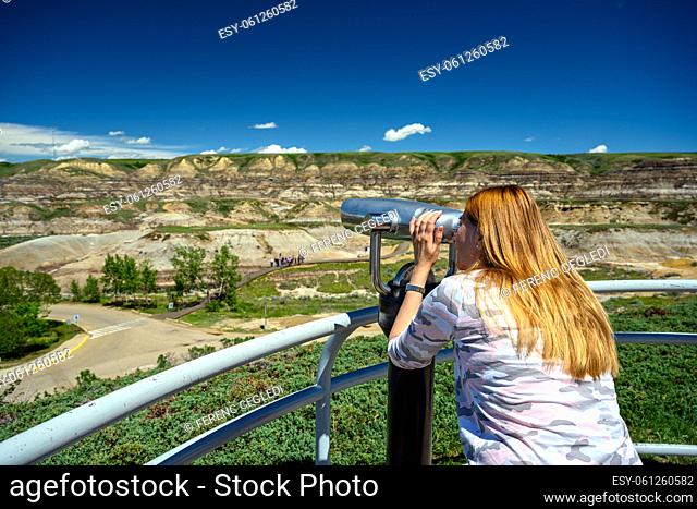 Tourist observing the landscape of the Canadian Badlands via binocular in Drumheller, the dinosaur capital of the world, Alberta, Canada