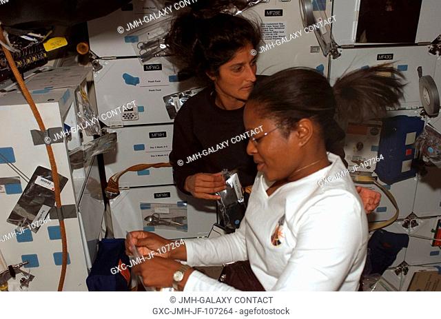 Astronauts Joan E. Higginbotham (foreground) and Sunita L. Williams, both STS-116 mission specialists, prepare to eat a meal on the middeck of Space Shuttle...