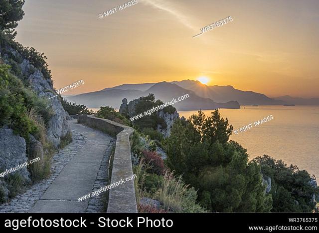 Rural hilltop road with sun rising or setting behind