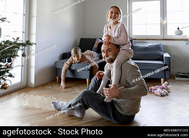 Portrait of mature man sitting on the floor at home playing with his little daughter