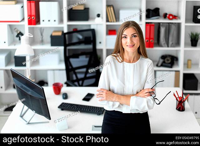 Beautiful young blonde girl in white blouse and black skirt is working in the office. photo with depth of field