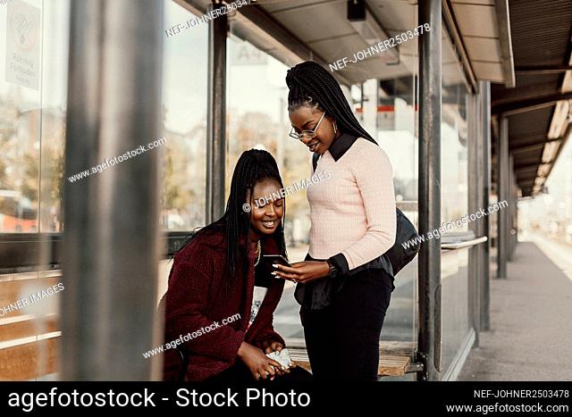 Smiling women using phone at train station platform