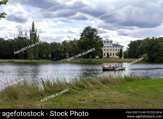 11 July 2020, Saxony-Anhalt, Wörlitz: A gondola rides past the castle and the Bible Tower in Wörlitz Park. The extensive park was built under the regency of...
