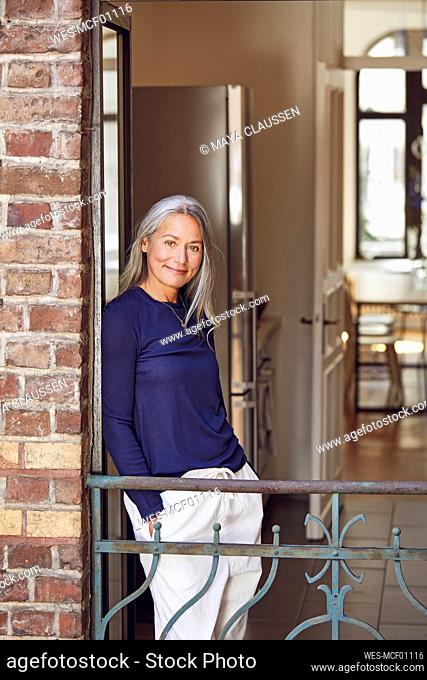 Smiling woman with hands in pockets in balcony
