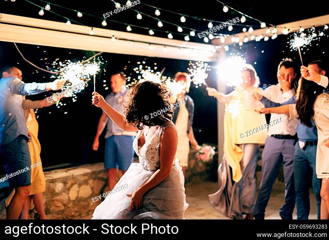 bride dancing among guests with sparklers at the wedding party. High quality photo