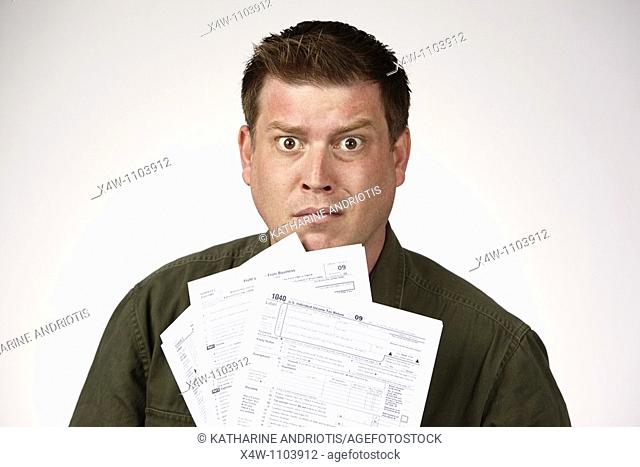 Man holding United States 1040 tax forms and feeling anxious about his taxes