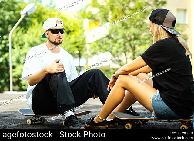 boy and girl on a skateboard are talking with each other on a summer day