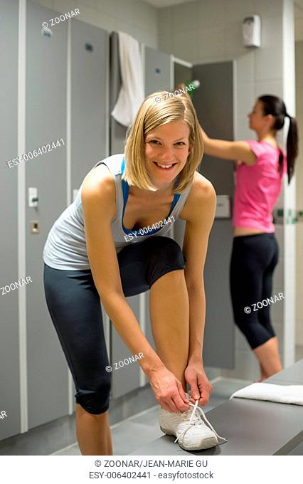 Smiling woman tying shoelaces in locker room