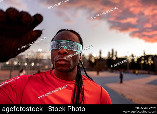 Young athlete wearing illuminated smart glasses at sunset