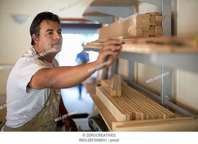Man with wooden frames on shelf in canvas workshop