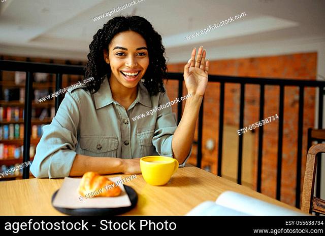 Cute female student, light breakfast in cafe. Woman learning a subject in coffeehouse, education and food. Girl studying in campus cafeteria