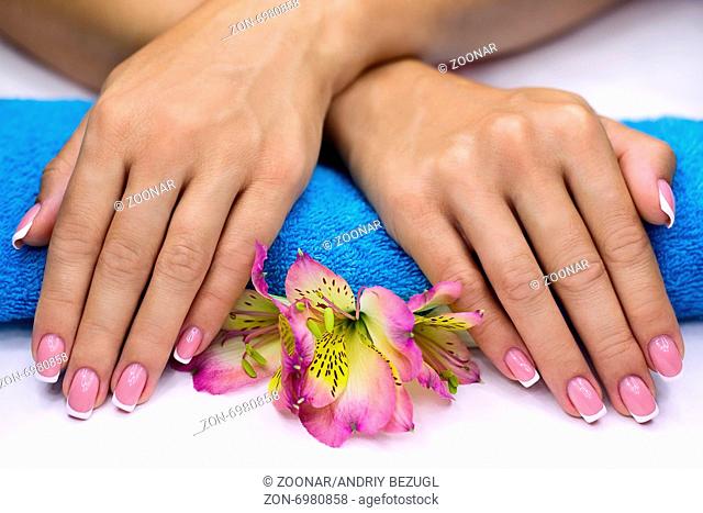 Hands with classic french manicure on a blue towel