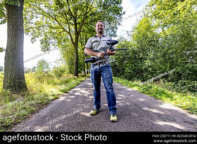 11 July 2023, North Rhine-Westphalia, Saerbeck: Ole Theisinger, a research assistant at Wald und Holz NRW, shows off his paintball gun