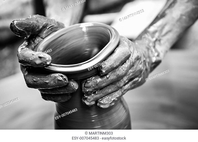 Hands of a man creating pottery on wheel, monochrome vintage view