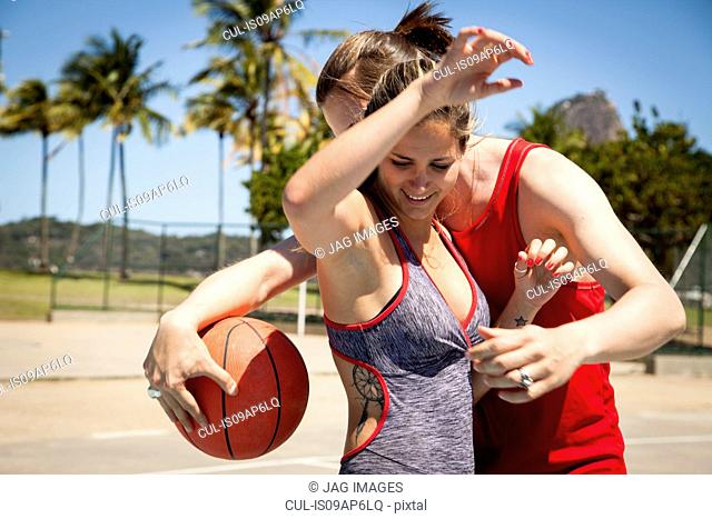 Young couple on basketball court in front of Sugarloaf mountain, Rio De Janeiro, Brazil